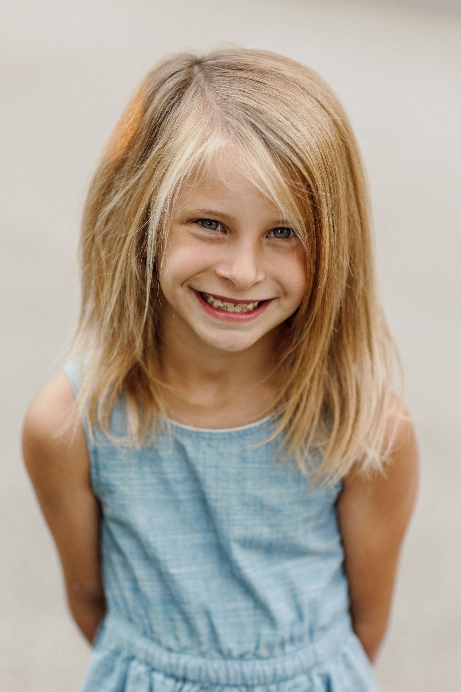 Close-up portraits showing bright smiles and blue summer dress.