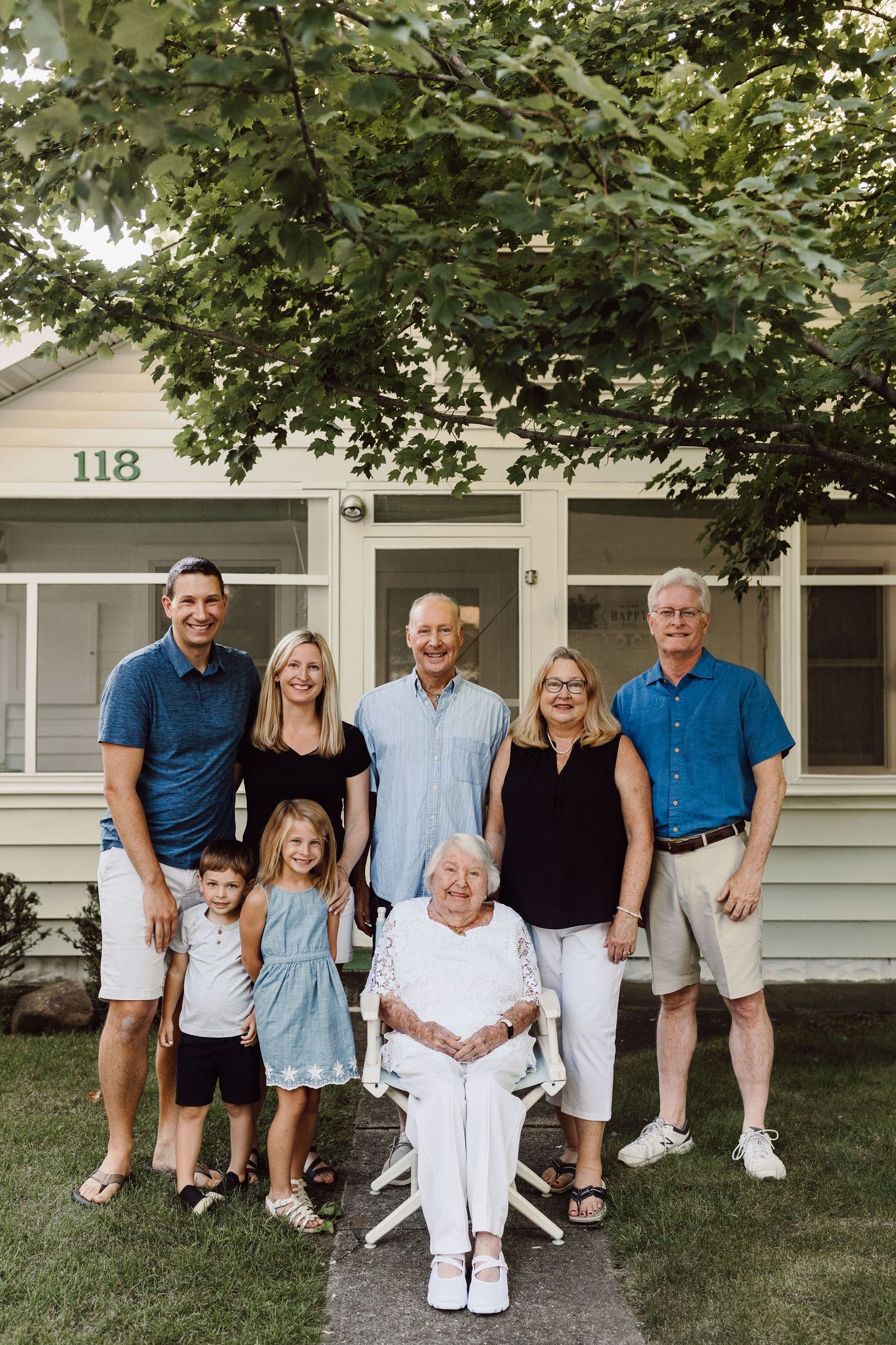 Multi-generational family poses together outside house number 118 wearing coordinated blue and white outfits.