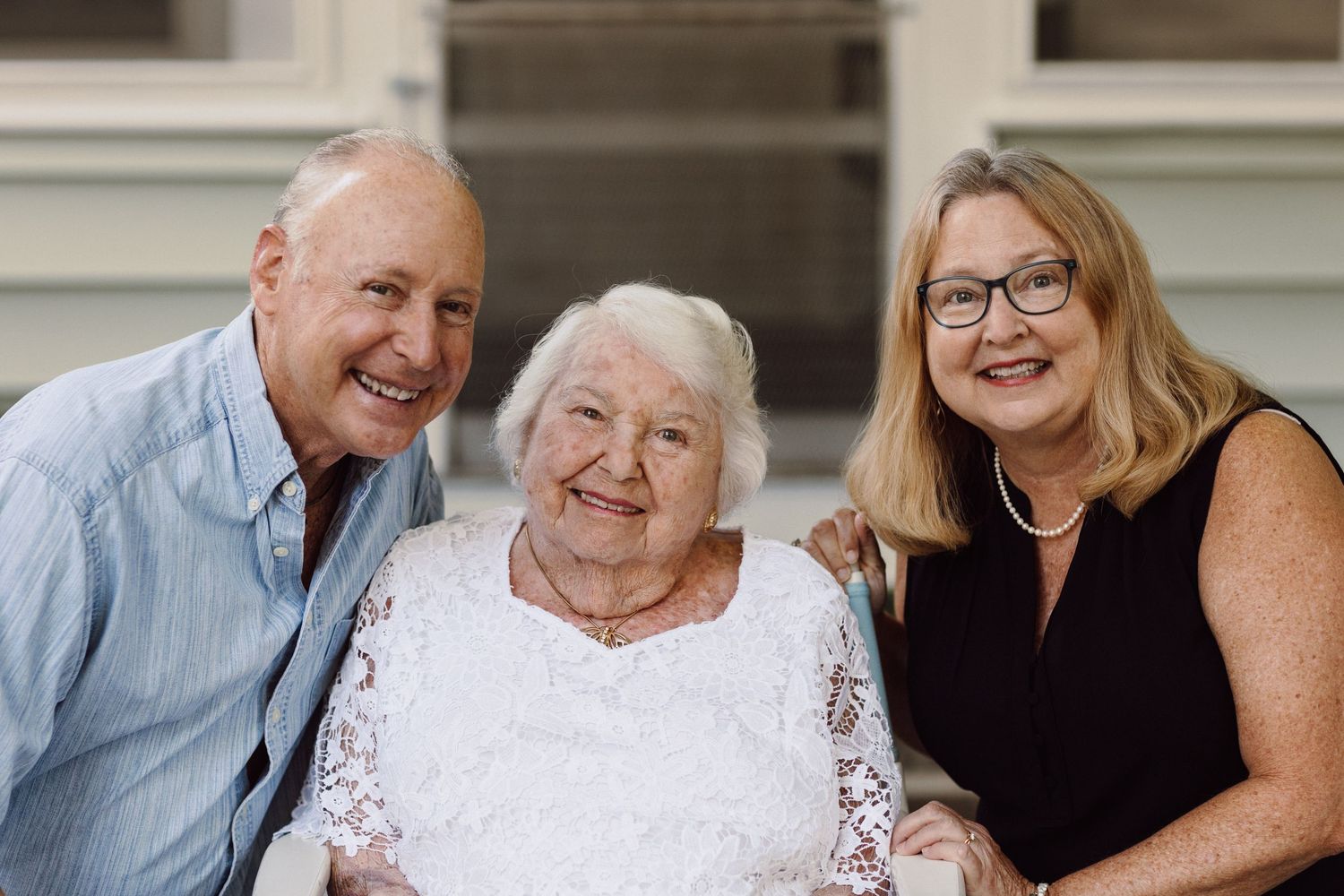 Family members smile together in casual summer attire during outdoor portrait session.