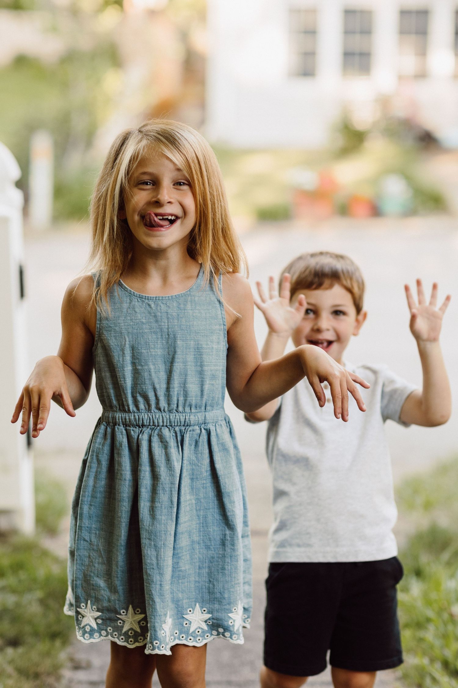 Children playing and laughing together outdoors in casual summer clothing.