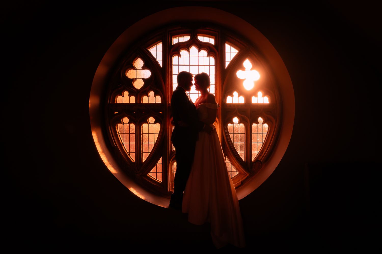 Circular church window silhouettes creating romantic ambiance. Ellingham Hall