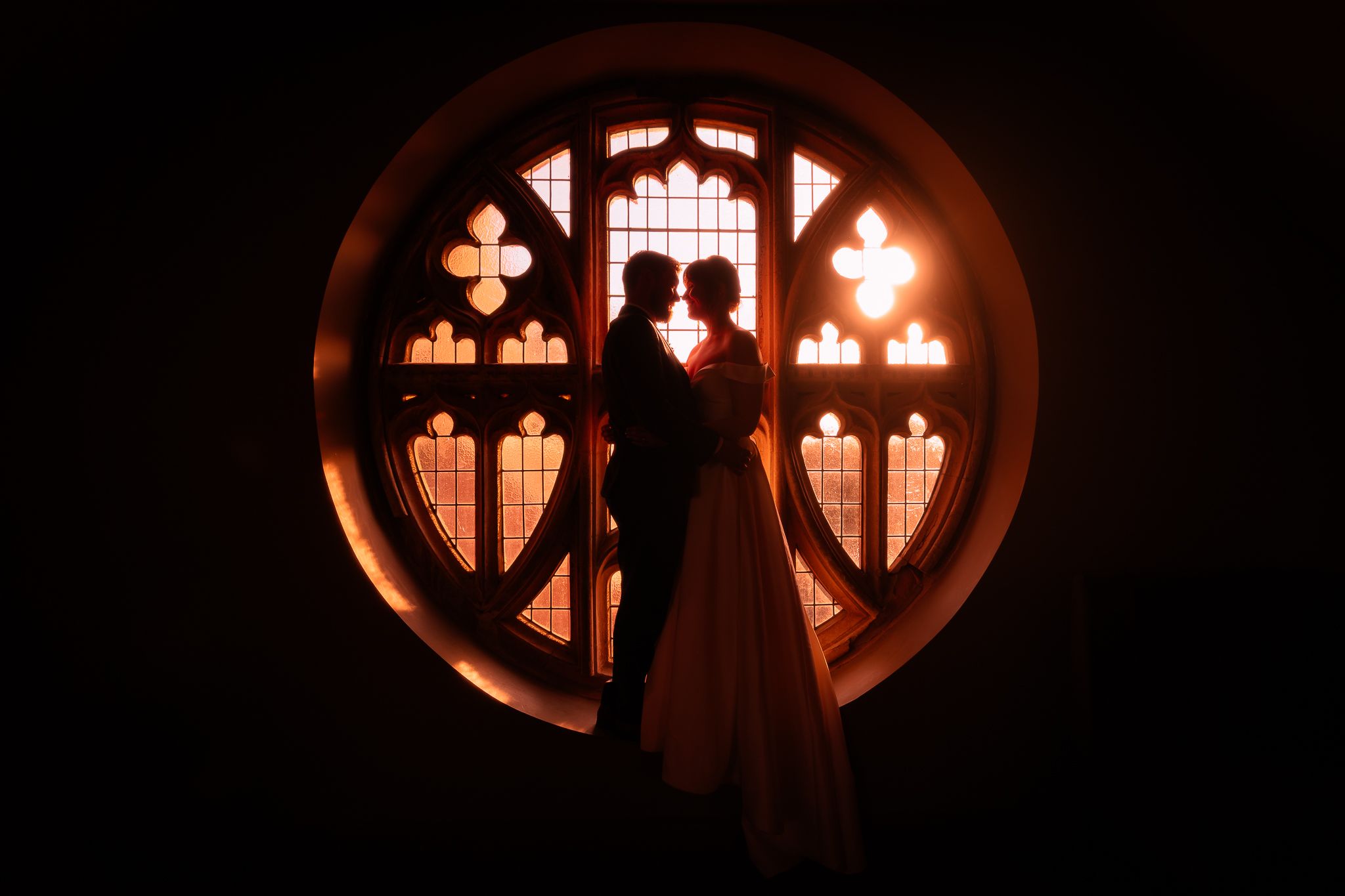 Circular church window silhouettes creating romantic ambiance. Ellingham Hall
