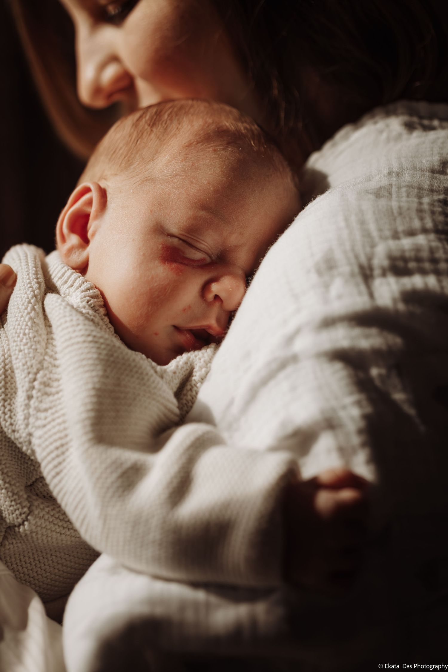 Intimate close-up of a sleeping baby wrapped in soft knit blankets.
