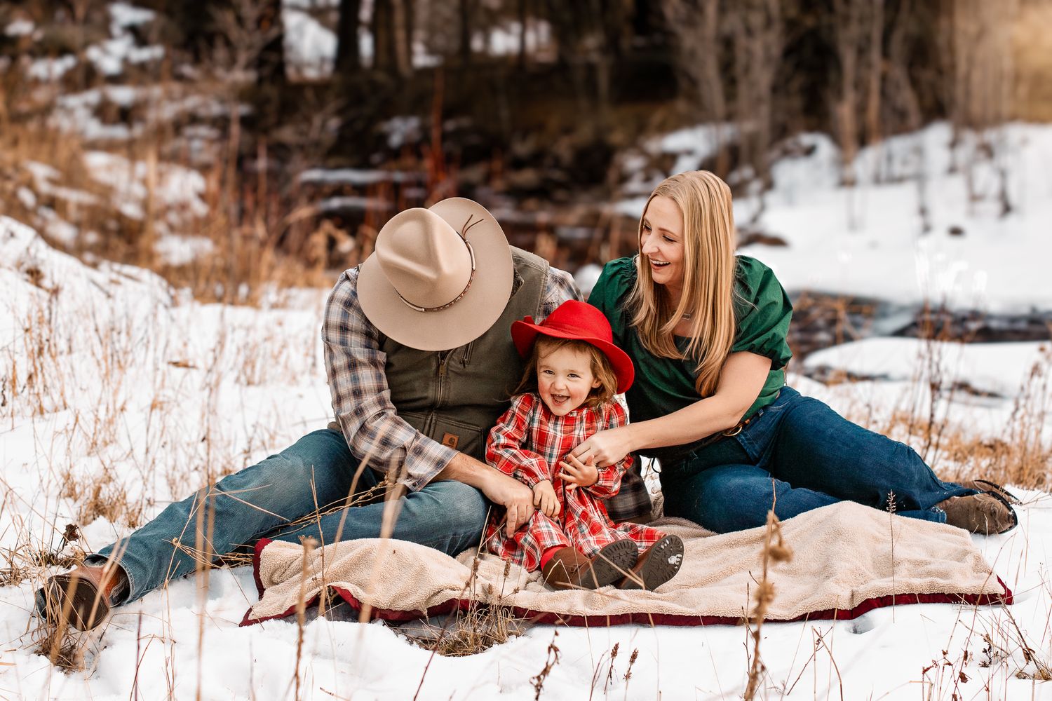 mom and dad tickling their little girl in a snowy Evergreen, CO backyard