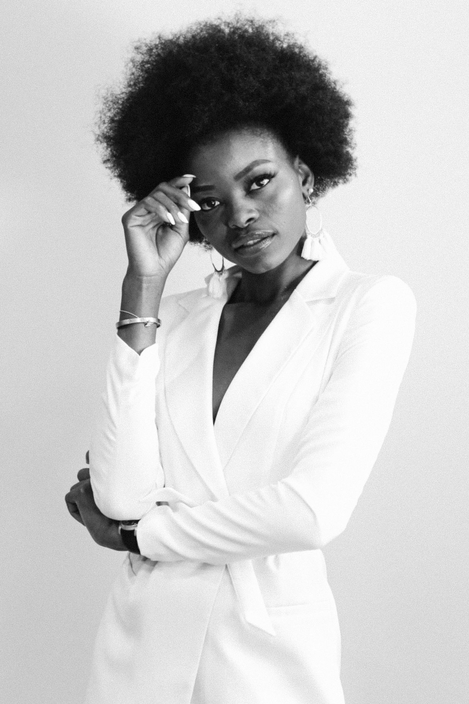 Black and white portrait series showing dynamic poses in a crisp white blazer against a light background.