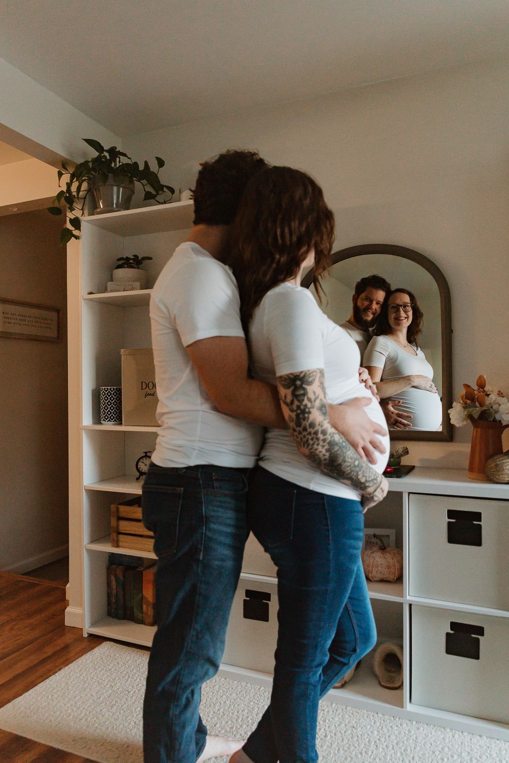 Two people embracing in a cozy home interior with white walls and wooden floors.