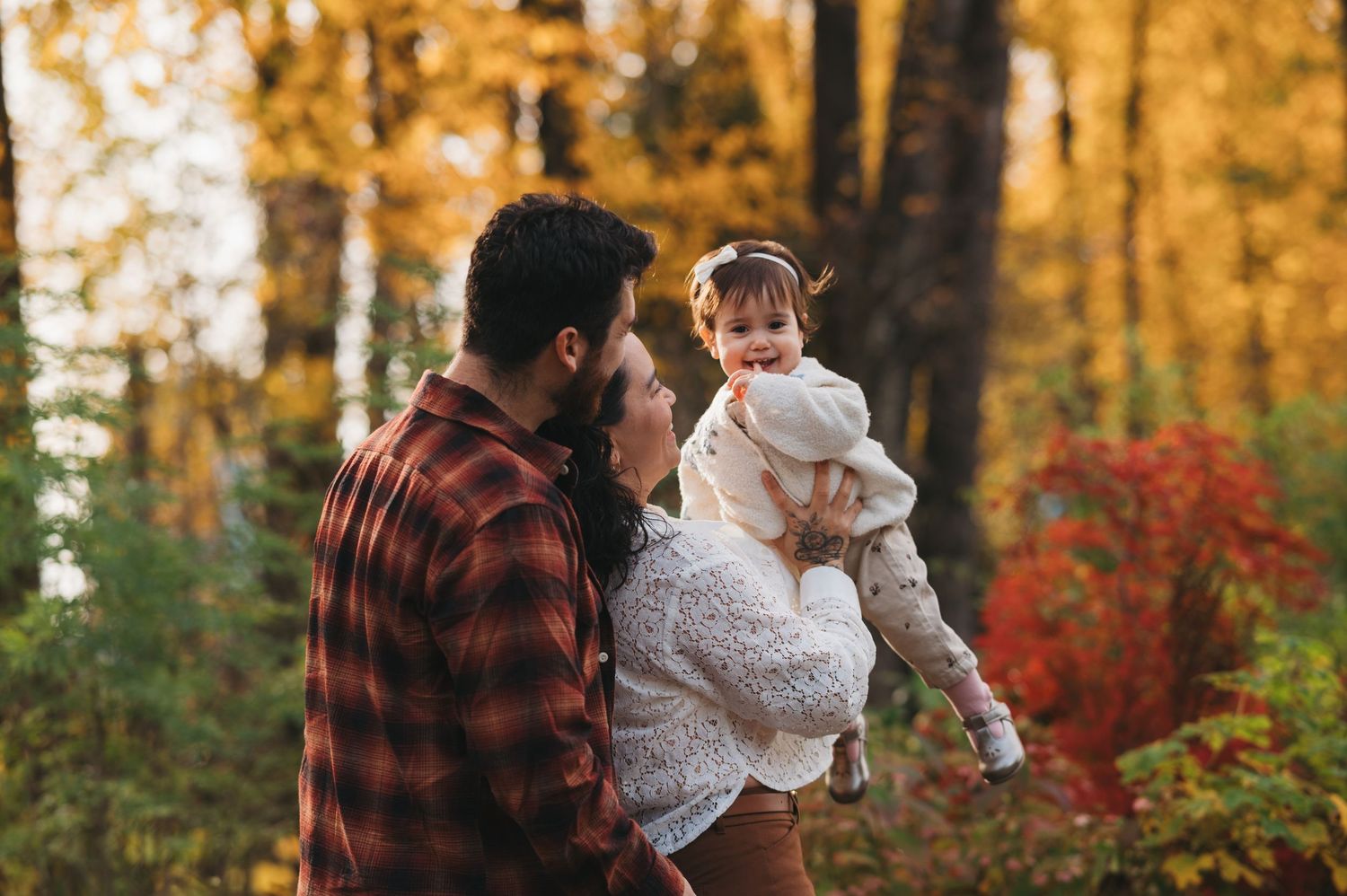 Family enjoying autumn scenery together in a forest with vibrant fall colors.