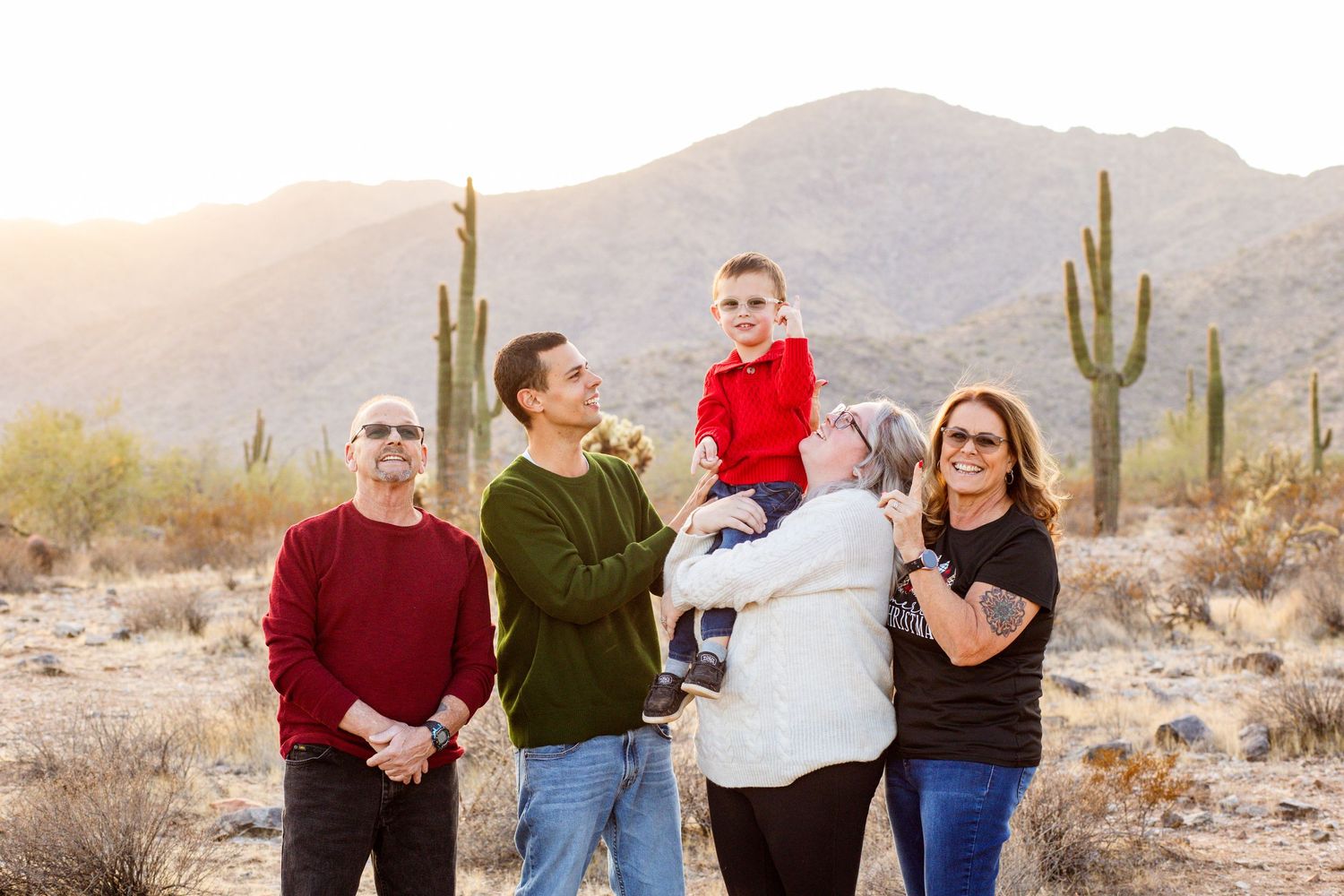 Multi-generational family portrait in Arizona desert with saguaro cacti and mountains at golden hour.