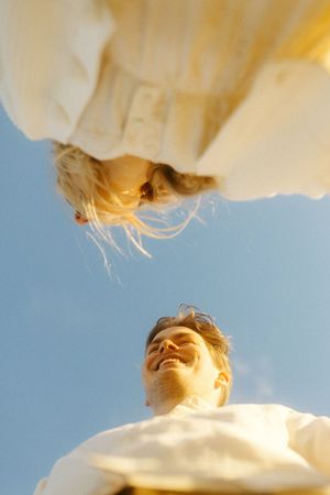 Artistic upward view of person in white against bright blue sky with sunflare.