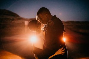 Silhouettes of a couple against a dramatic sunset with lens flares creating a romantic atmosphere.