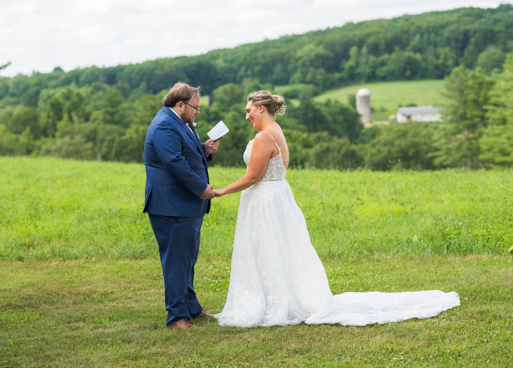 Couple in formal wedding attire sharing an intimate moment together in a lush green countryside setting.
