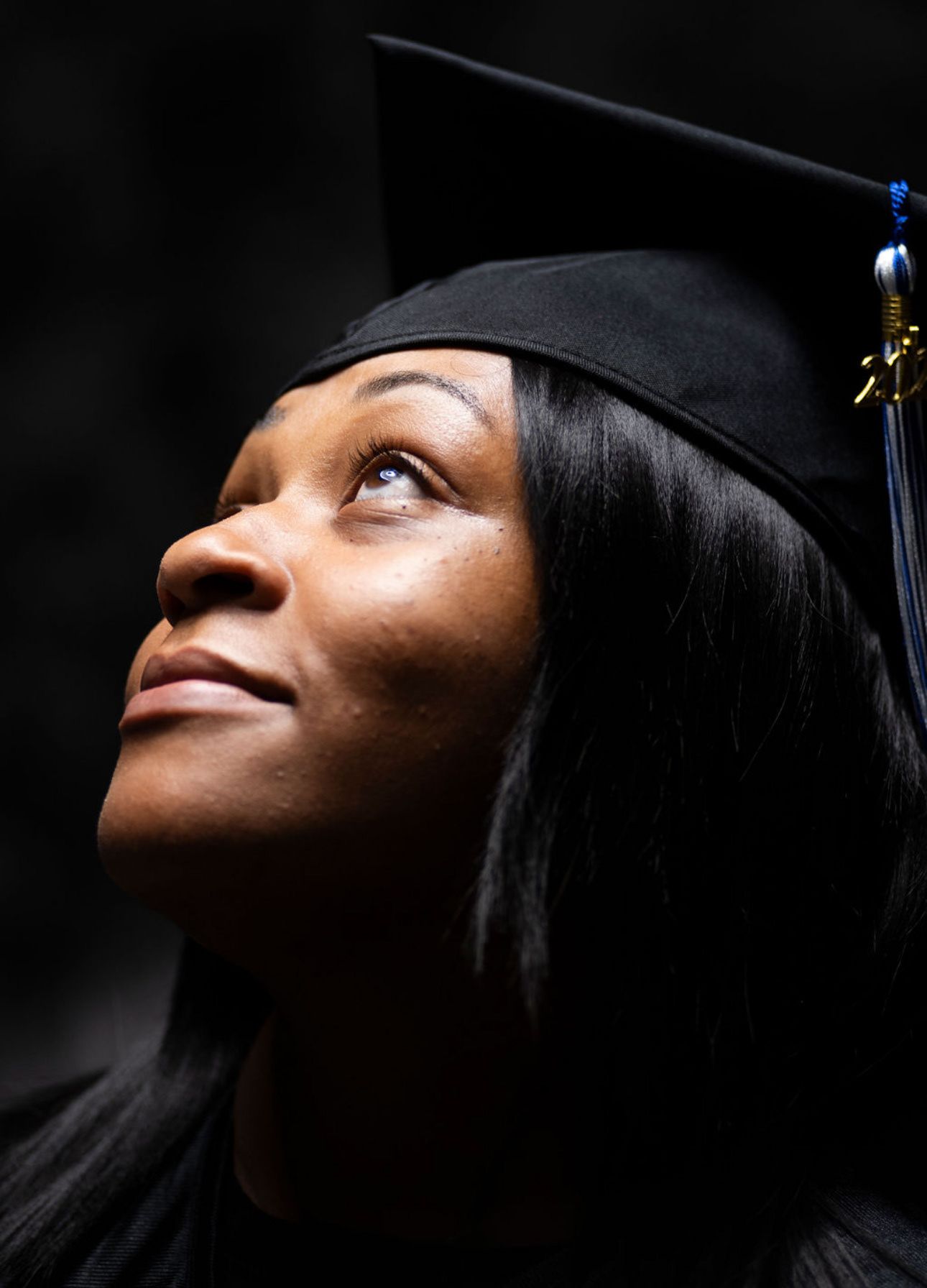 A graduation portrait series shows a graduate looking upward with dramatic lighting against a dark background.
