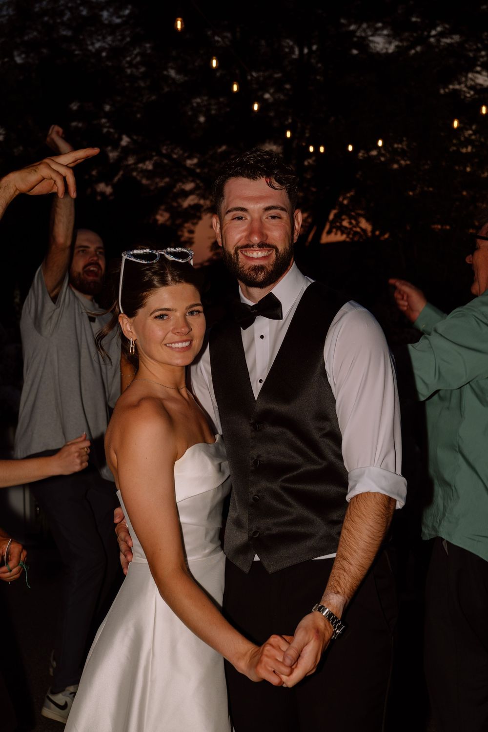 A couple dances together at a wedding reception, with the bride wearing a white dress and groom in dark attire.