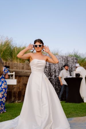 A person in a strapless white wedding dress poses playfully in a sequence of outdoor photos at a rustic venue.
