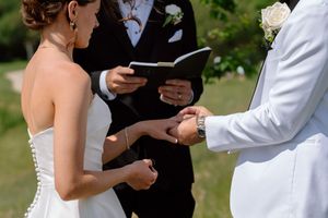An officiant reads from a book during an outdoor wedding ceremony with mountains in the background.
