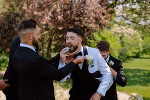 Wedding party enjoying a playful moment together under blooming cherry trees in a spring garden setting.
