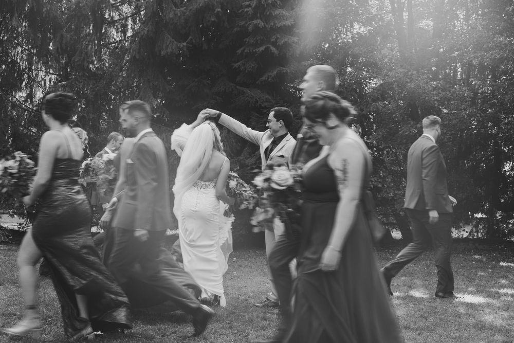 Black and white photo of wedding guests dancing and celebrating at reception.