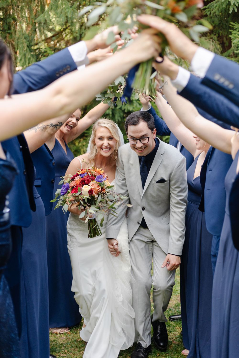 Wedding party creates an archway tunnel with raised arms for newlyweds to walk through.