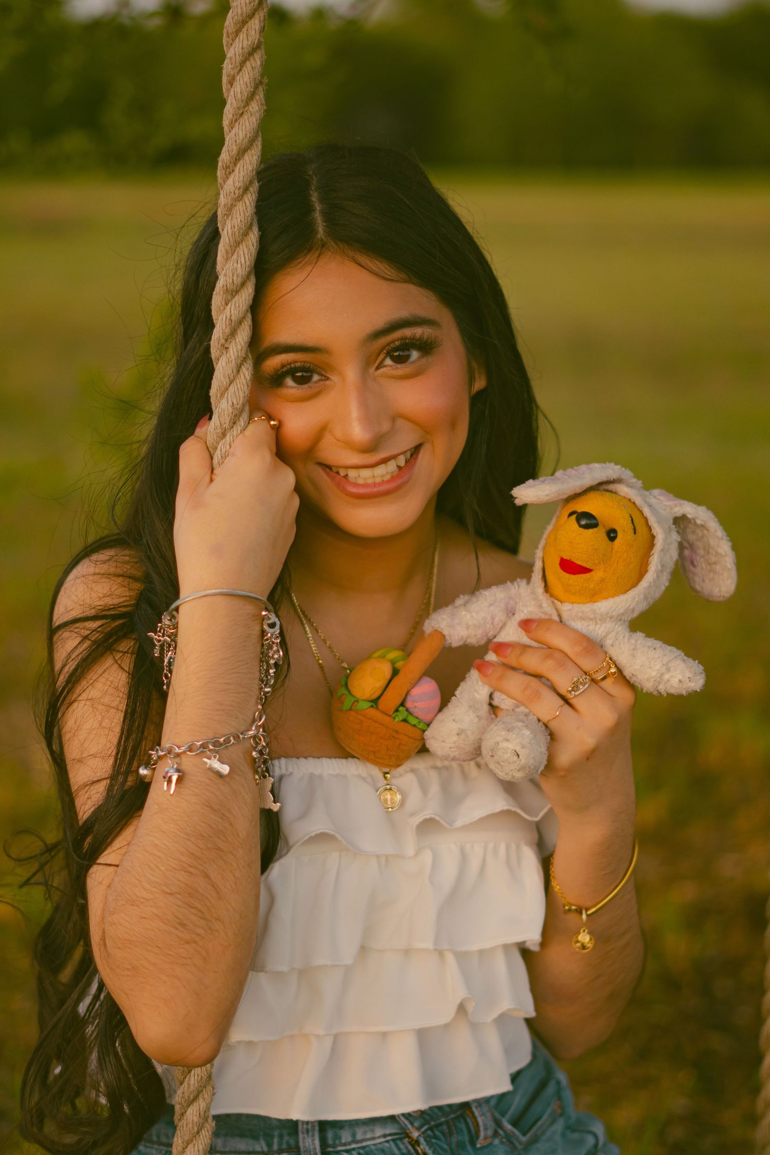 Person holding small plush toys while posing in outdoor setting.