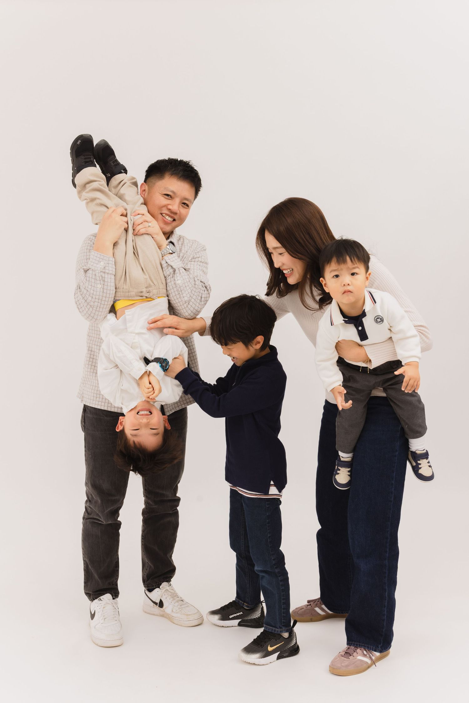 Two children play together in a series of candid white studio photos showing playful interaction and movement.