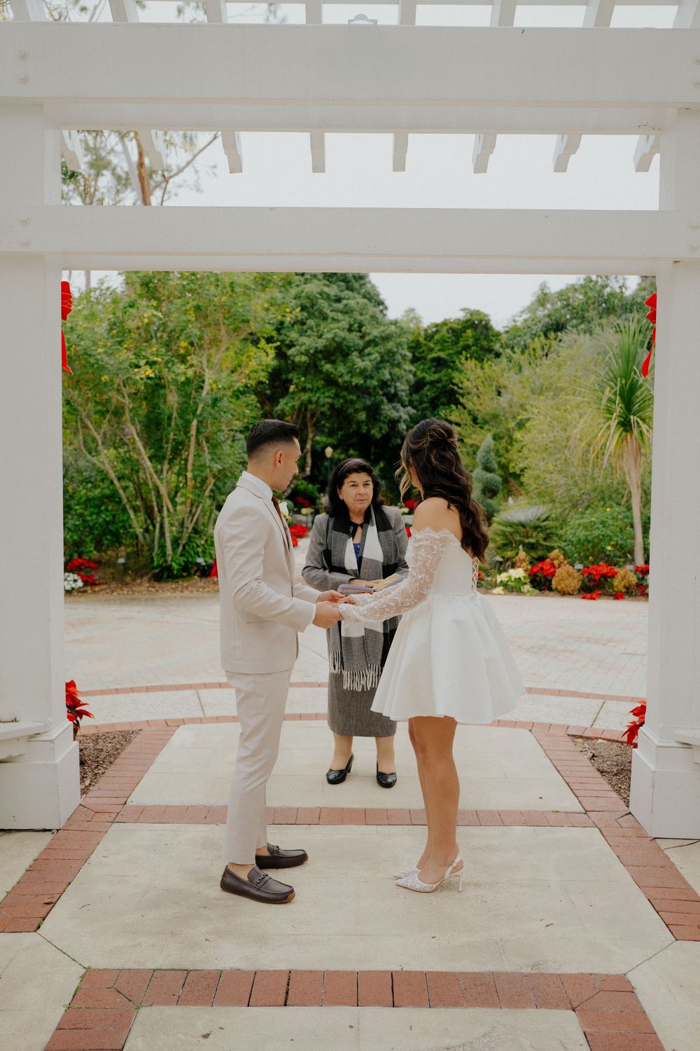 A couple dances together under a white pergola in a romantic outdoor setting.