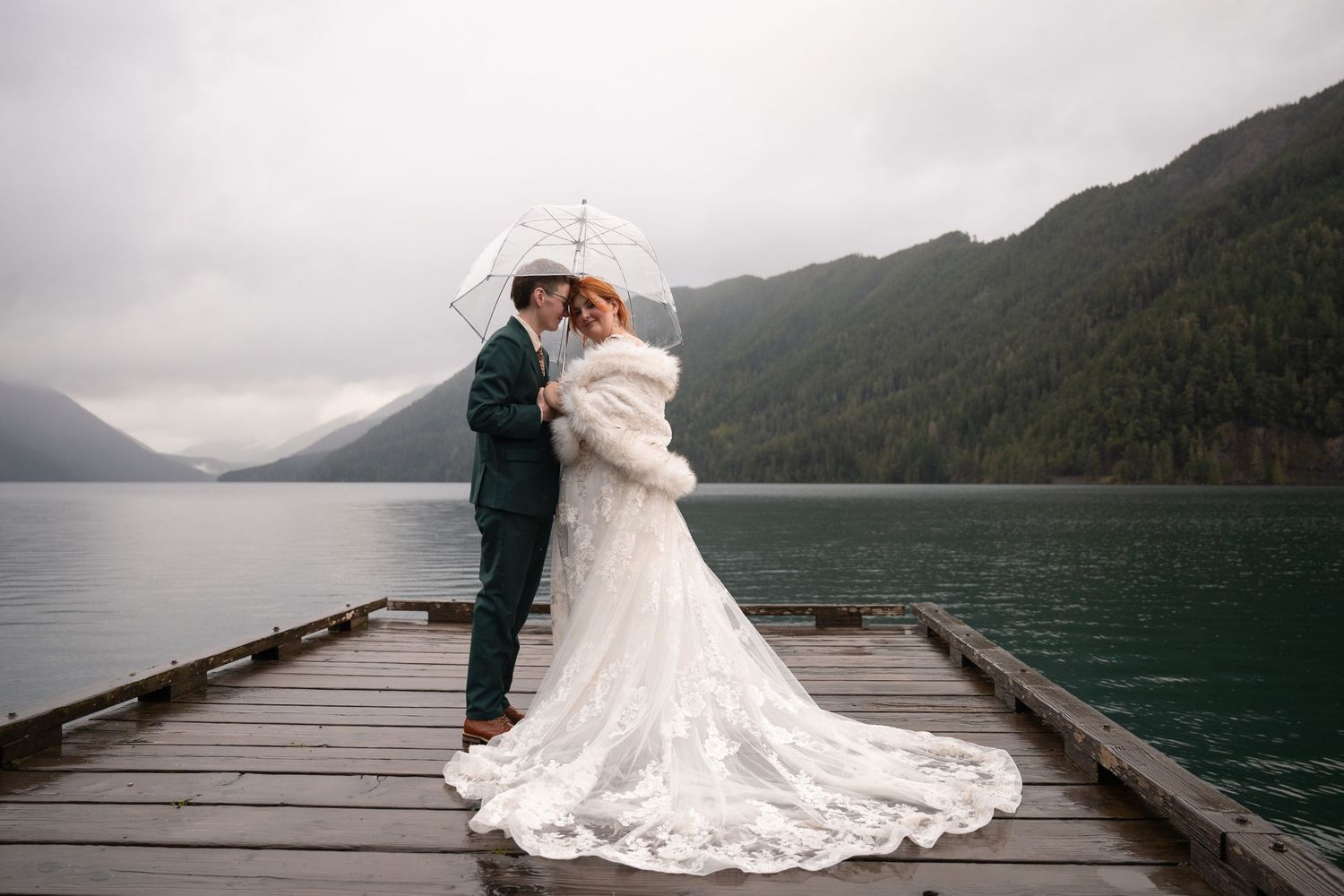 Two women embrace each other on a dock on Lake Crescent in Olympic National Park, celebrating their Pacific Northwest adventure elopement