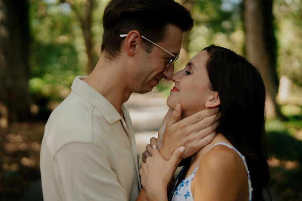 A romantic couple shares intimate moments in a series of outdoor photos surrounded by lush greenery and natural light.