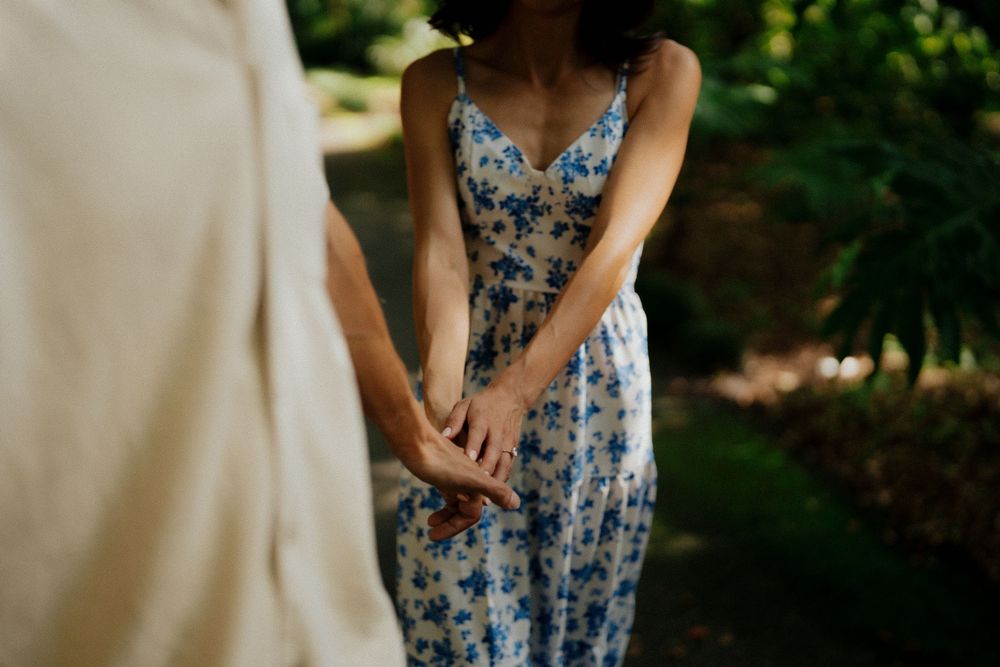 Bridesmaids in blue floral dresses stand together during an outdoor wedding ceremony.