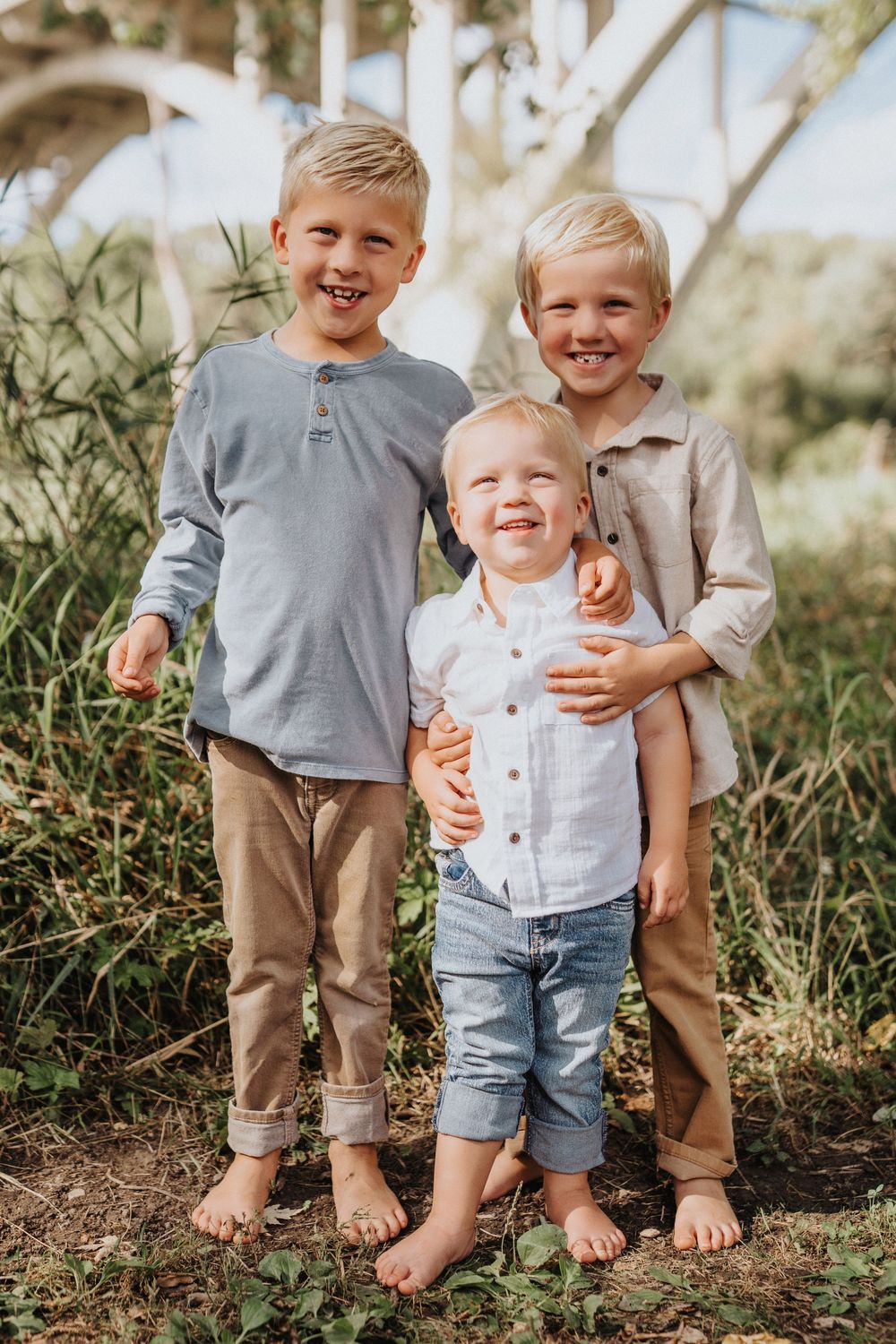 Children's feet and legs shown outdoors in casual clothing with jeans and gray shirts against a natural background.