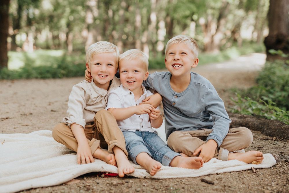 A joyful outdoor family photoshoot showing playful moments in a wooded setting.
