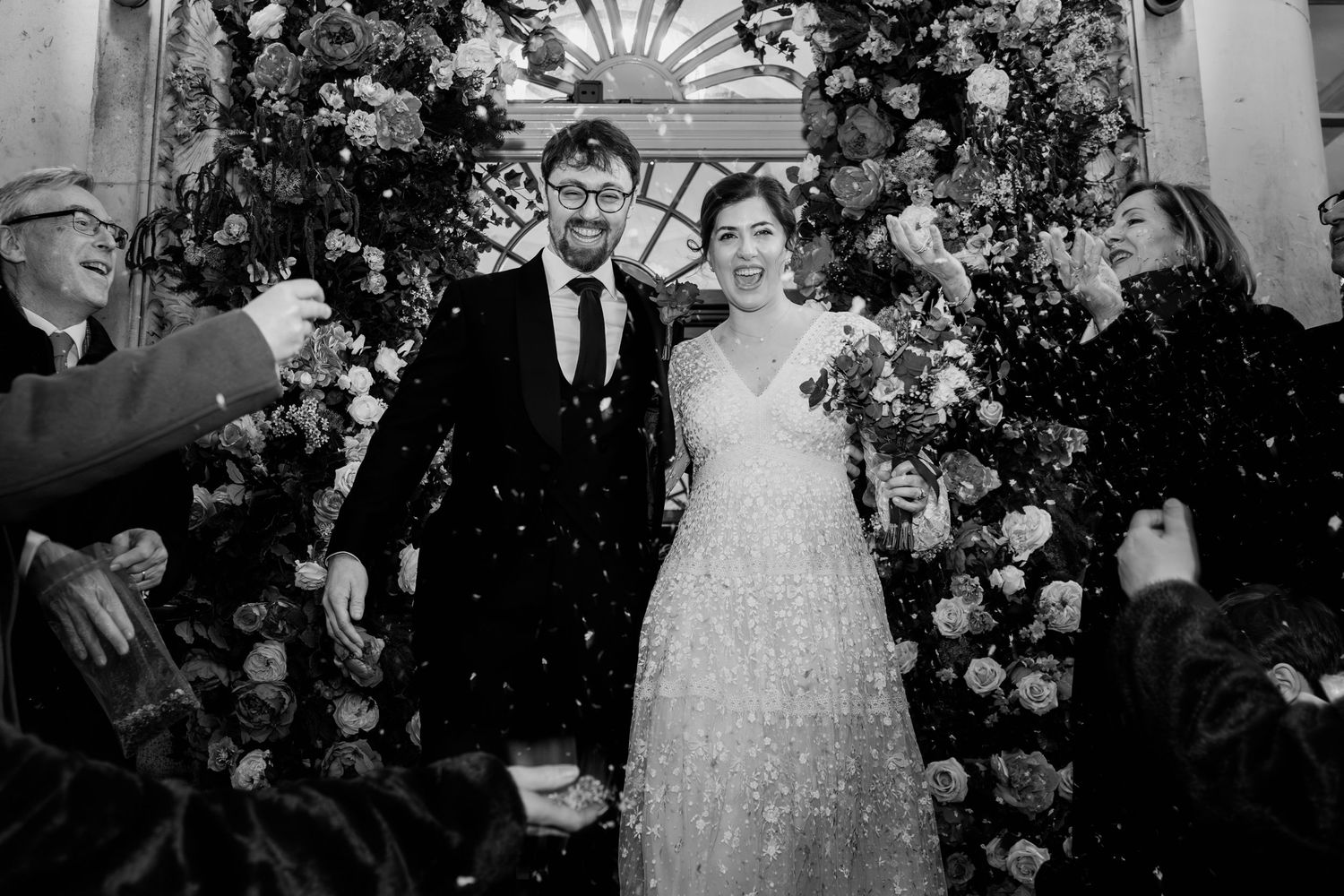 A series of black and white wedding photos showing a bride in a ballgown and guests at an elegant indoor reception.