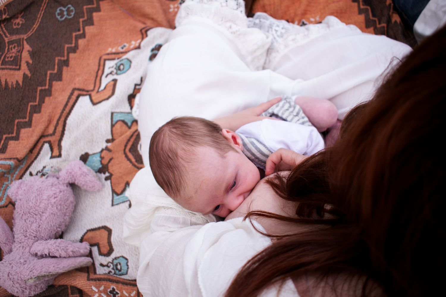 Newborn baby breastfeeding in Mum's arms at a country themed newborn golden hour photoshoot in Maitland NSW