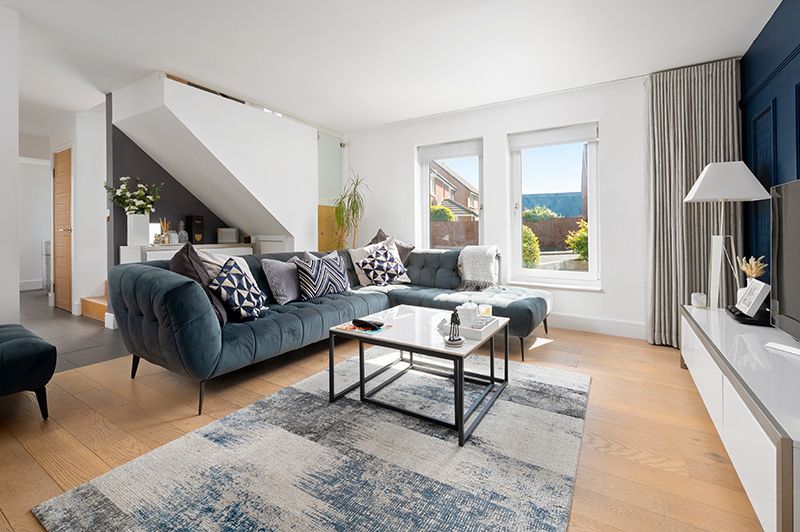 Modern Scandinavian living room interior with light wood floors, grey sofa, and large windows overlooking cityscape.