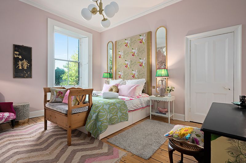 An interior photo showcasing bright master bedroom with light pink walls and modern furnishings.