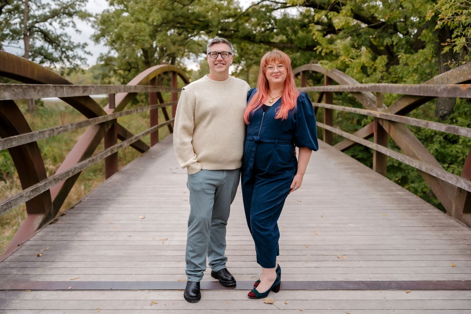 Couple's feet standing together on a wooden bridge in romantic poses showing jeans and dress shoes.