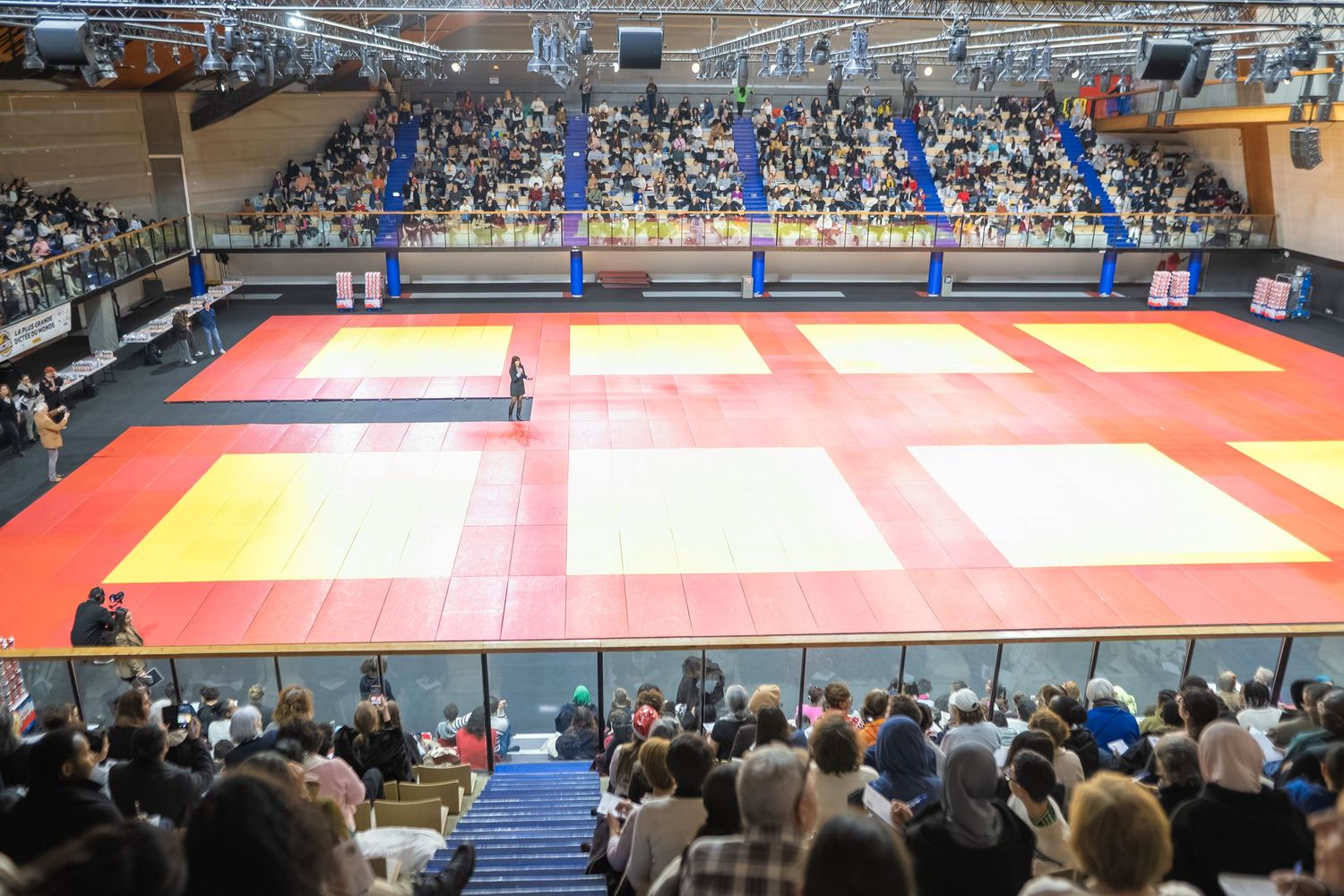A row of panoramic photos showing a judo or martial arts competition venue with red and yellow mats and spectator seating.