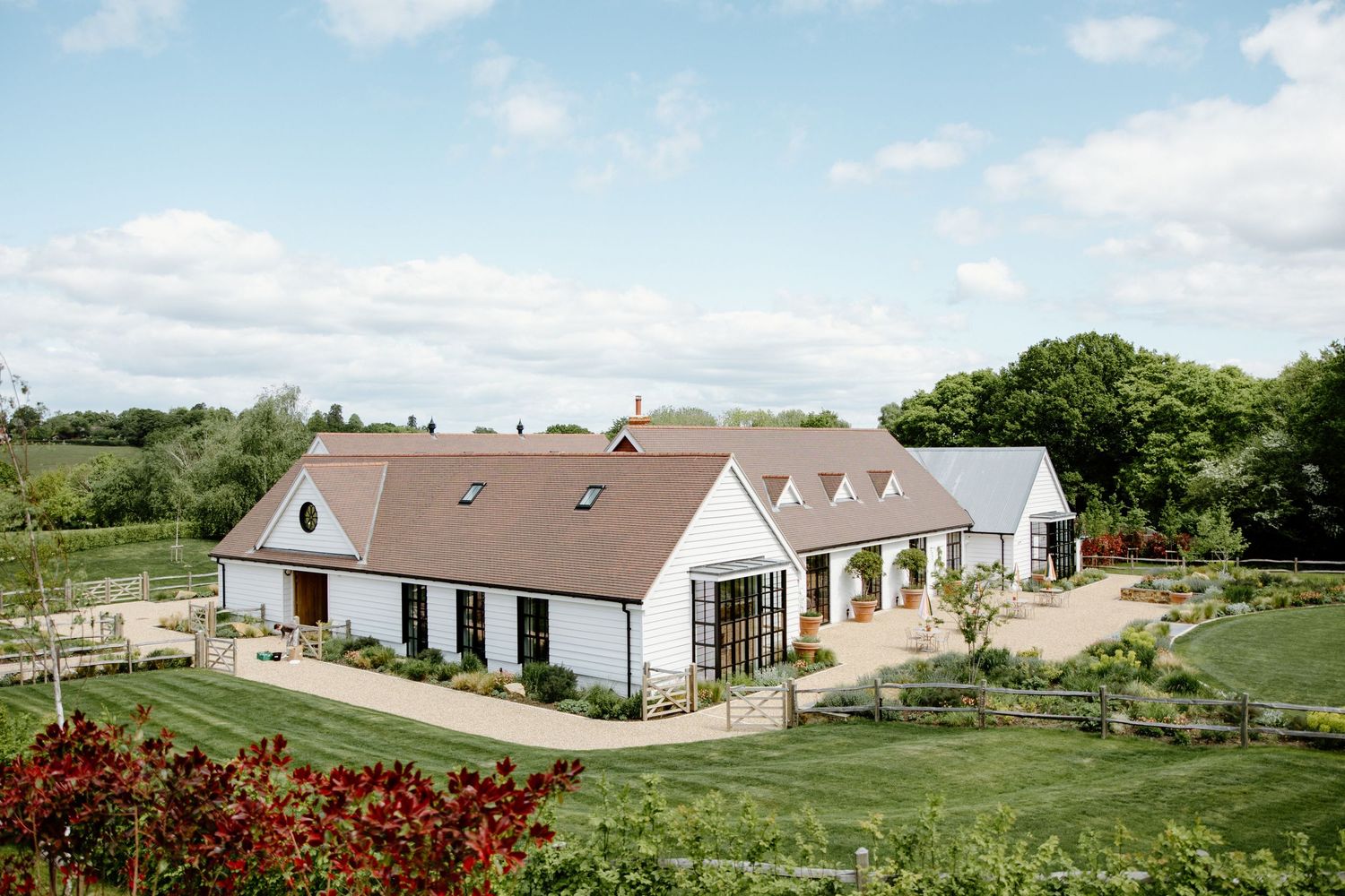 Panoramic view of white wedding venue buildings nestled in rolling green countryside.