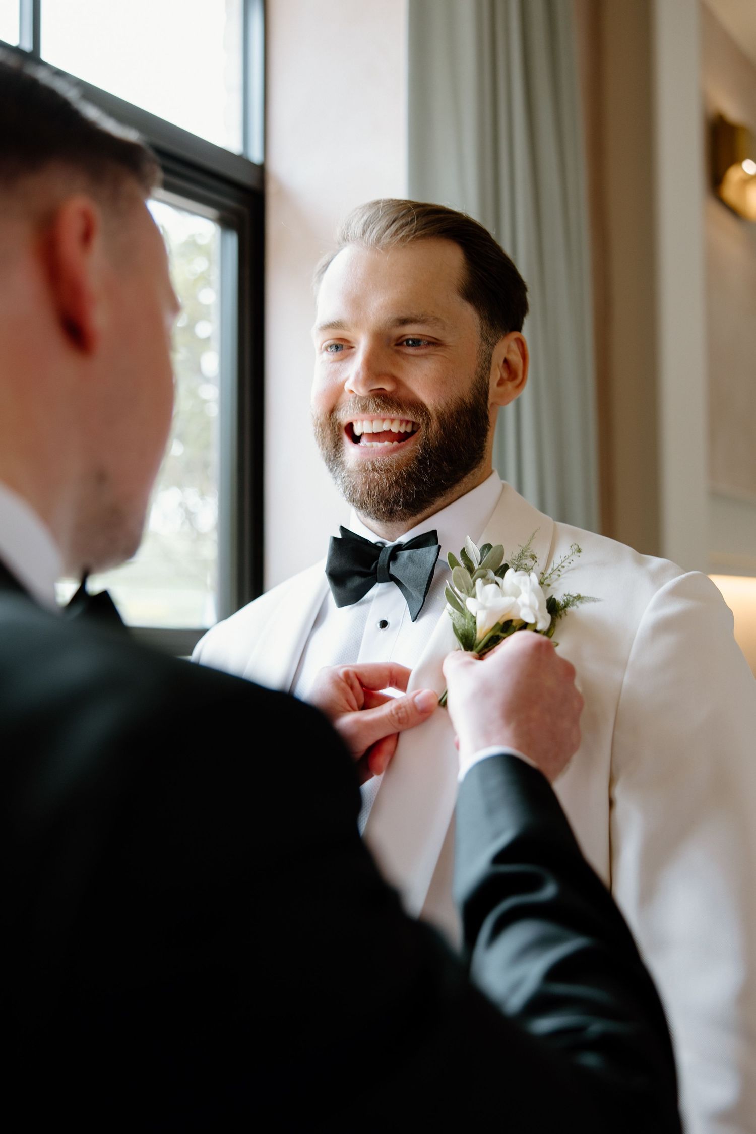 Groomsmen helping adjust a bowtie before the wedding ceremony.