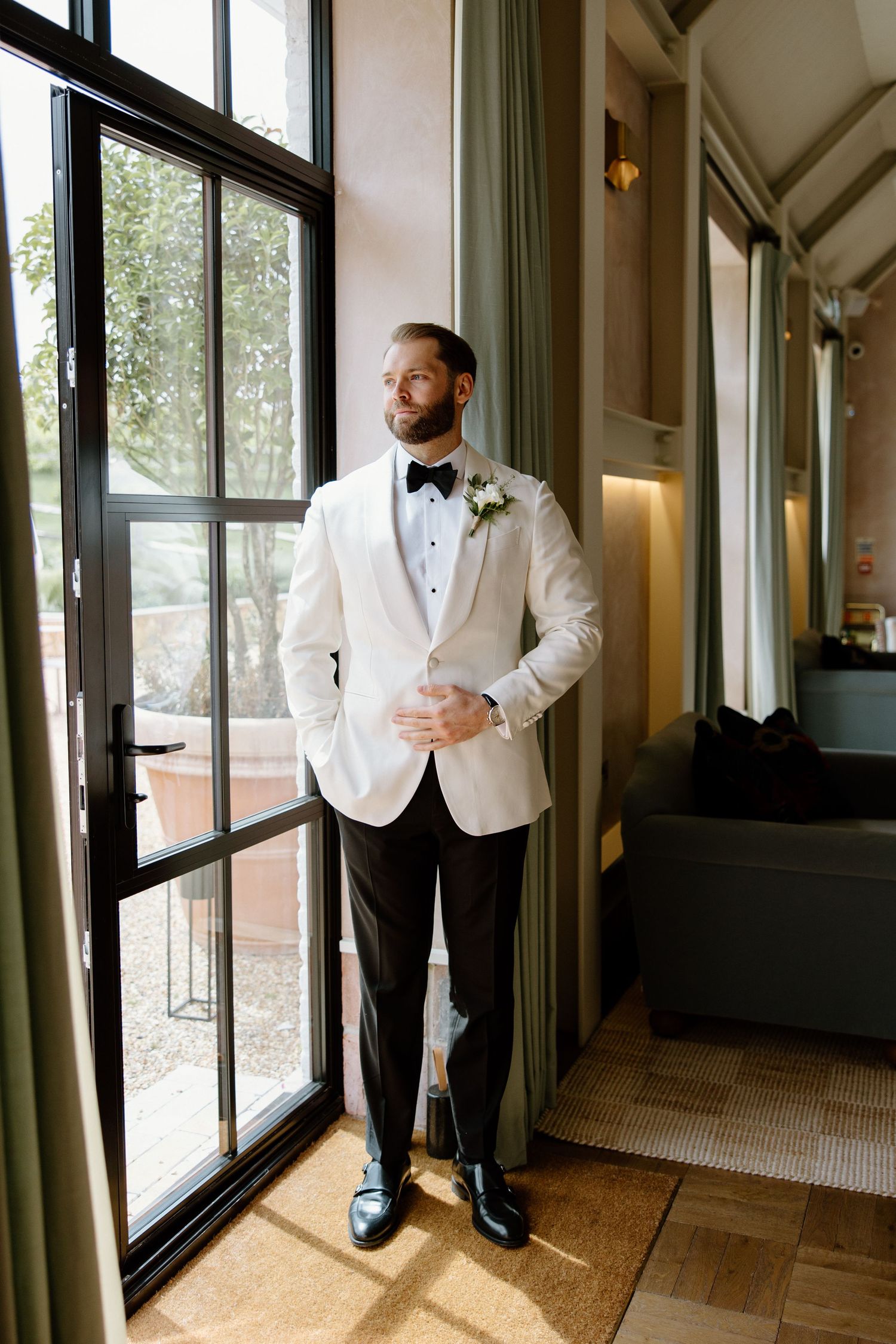 Series of photos showing groomsmen in white tuxedos standing by large windows.