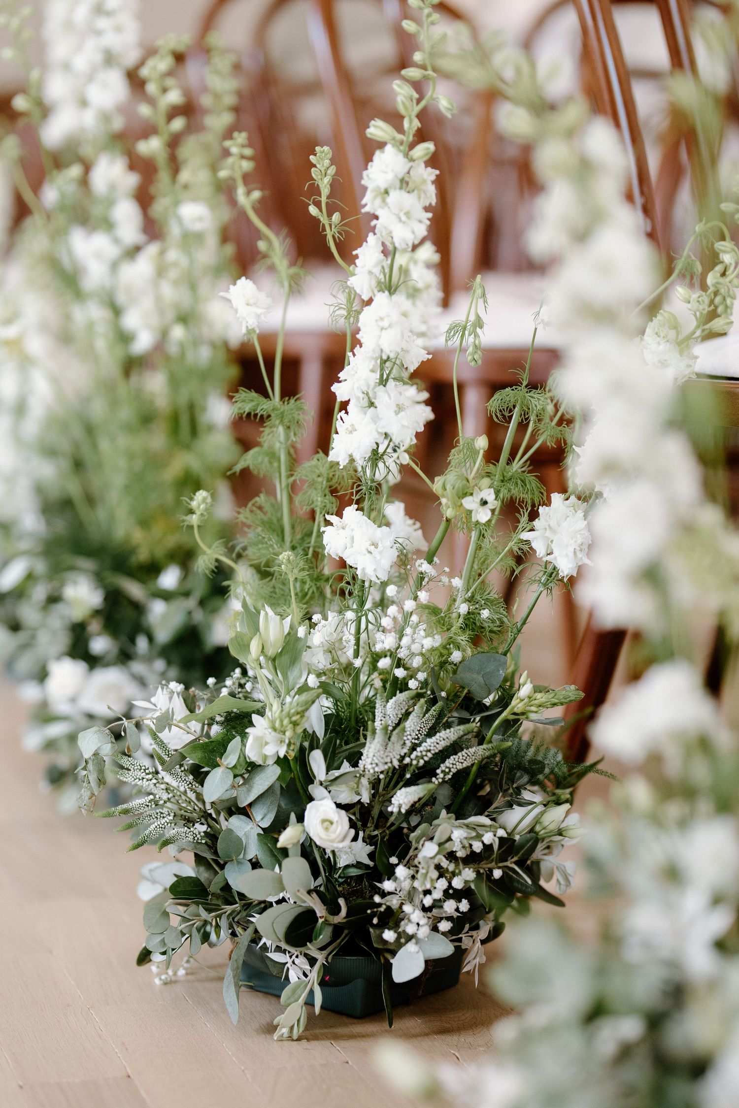 Delicate white floral arrangements with greenery in rustic vases create an elegant table centerpiece display.