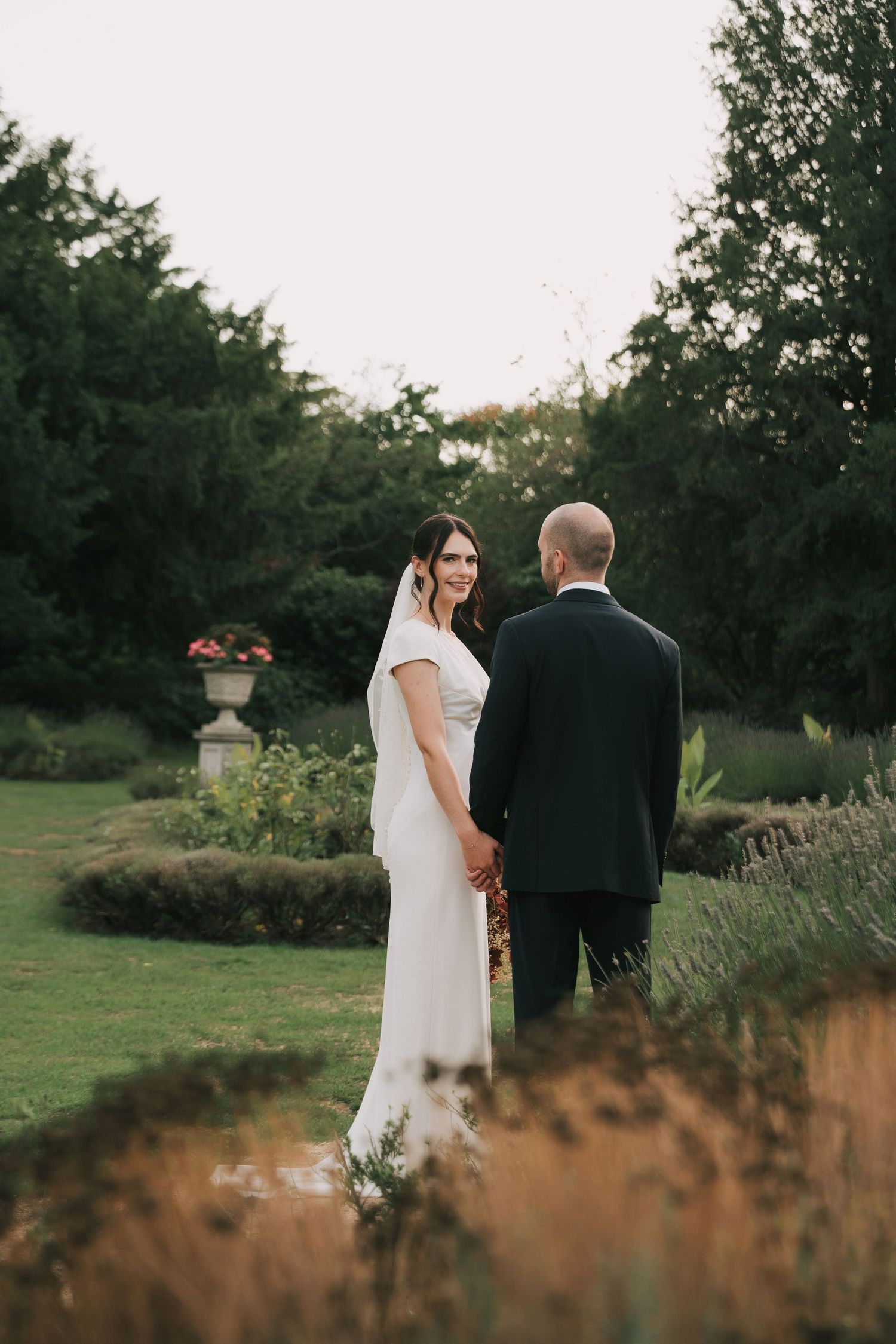An intimate wedding portrait captured in a garden with autumn foliage and soft evening light.