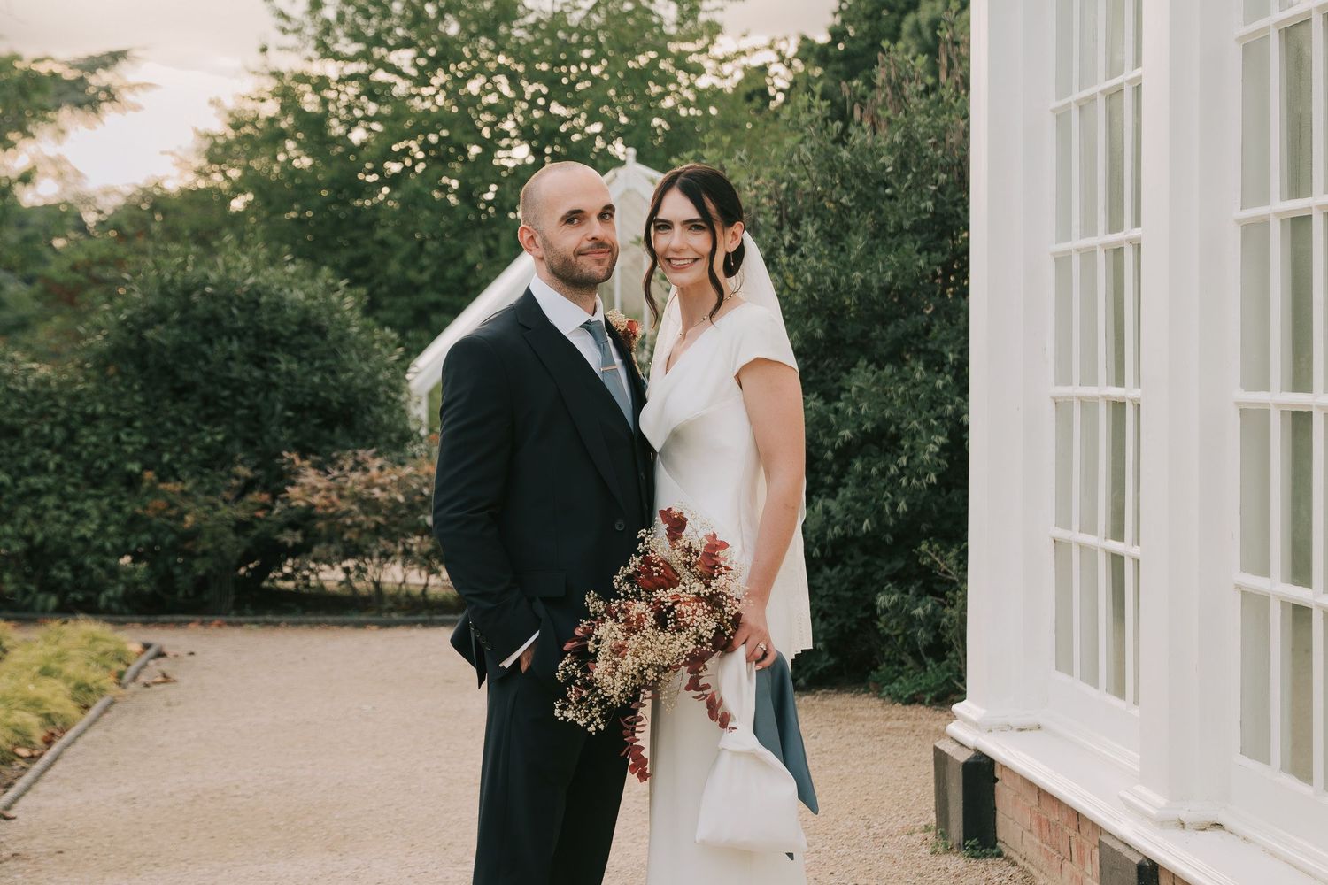 A romantic outdoor wedding photoshoot at a white mansion with elegant architectural details.