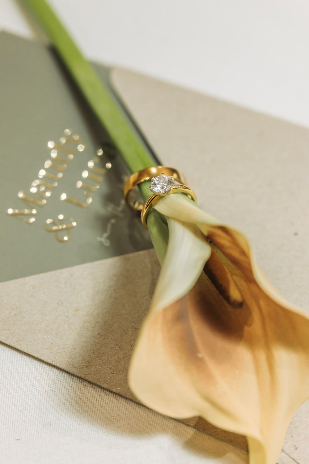 A ring placed on a white calla lily stem in a creative jewelry photography composition.