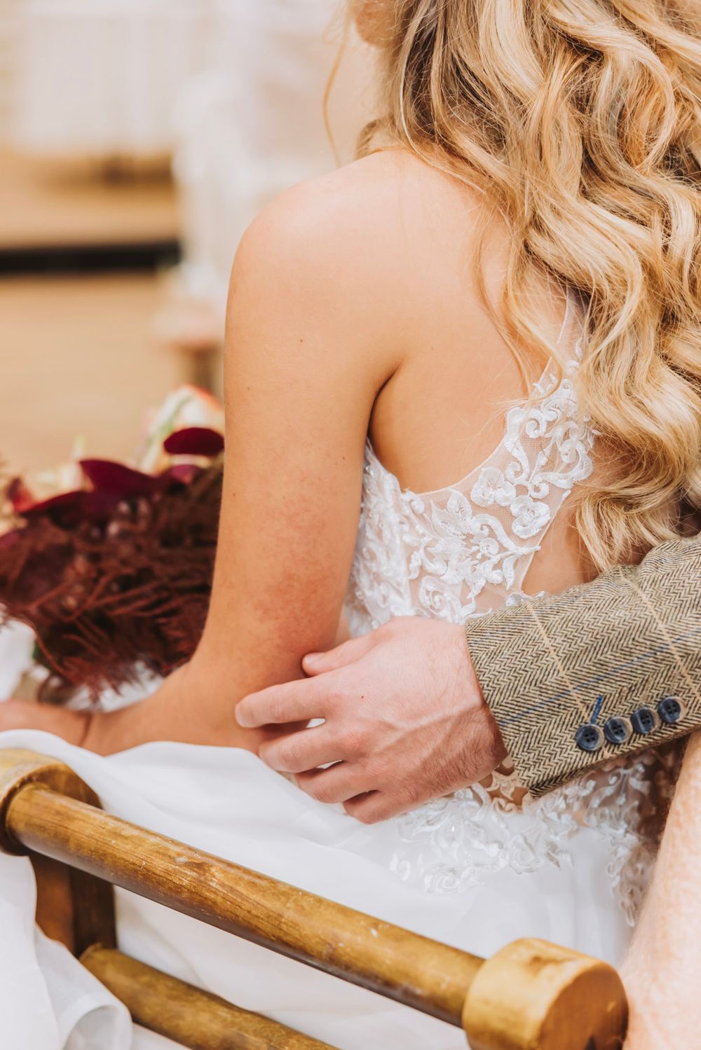 Close-up of intimate moment between bridal couple. Detail of delicate white lace wedding dress with hand gently resting on waist