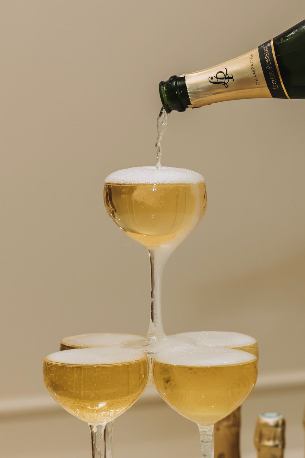 Champagne being poured into elegant coupe glasses creating a beautiful golden cascade of bubbles.