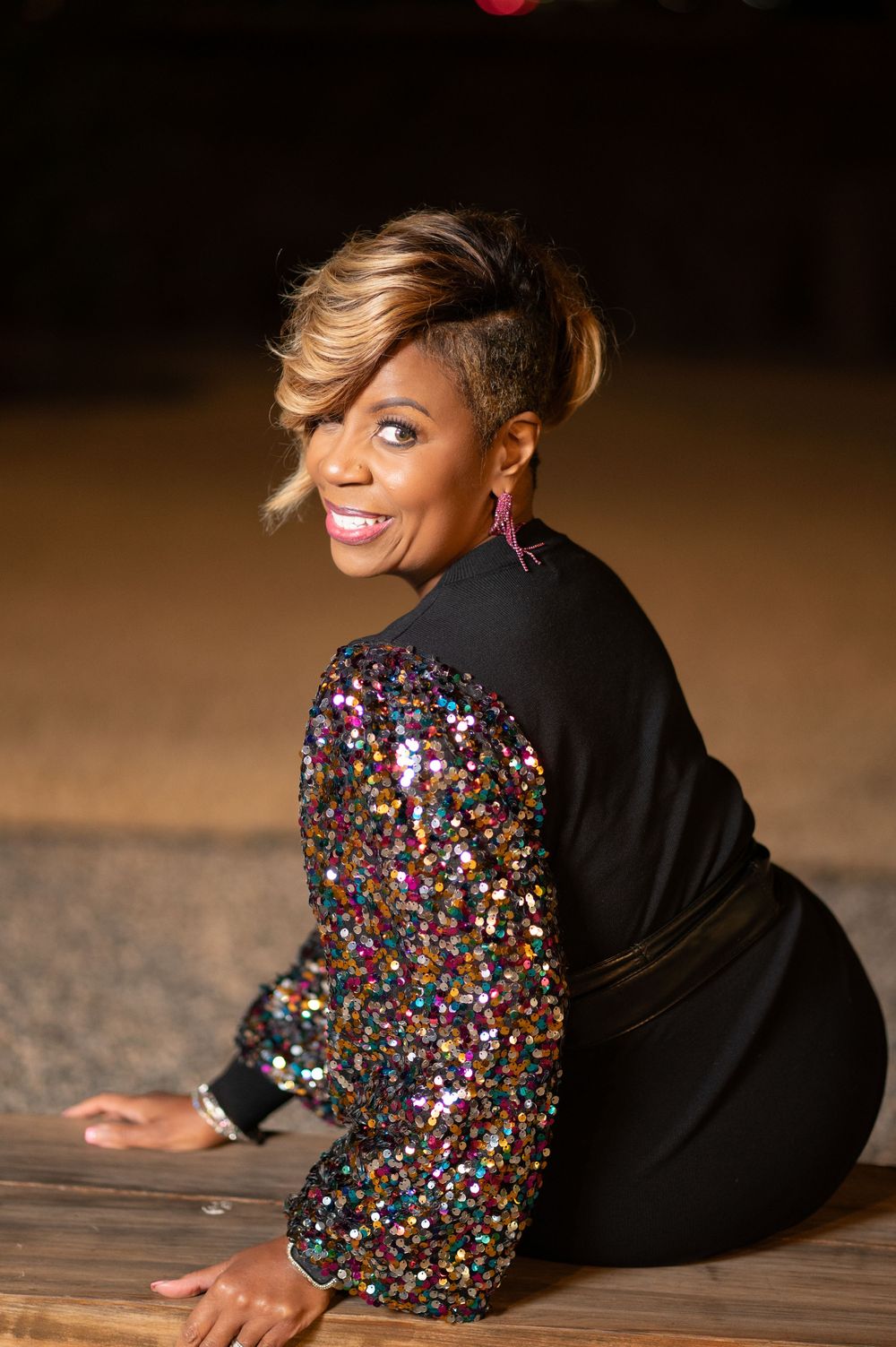 Glamorous sequined dress with black sleeves sparkles in dramatic portrait series.