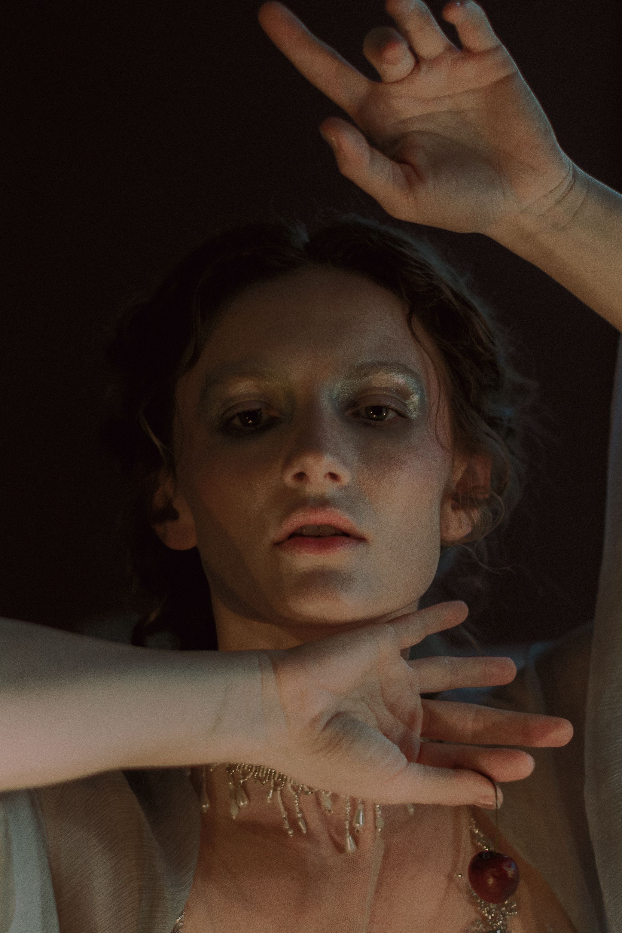 Artistic portrait series showing hands framing a face in dramatic lighting against dark background.