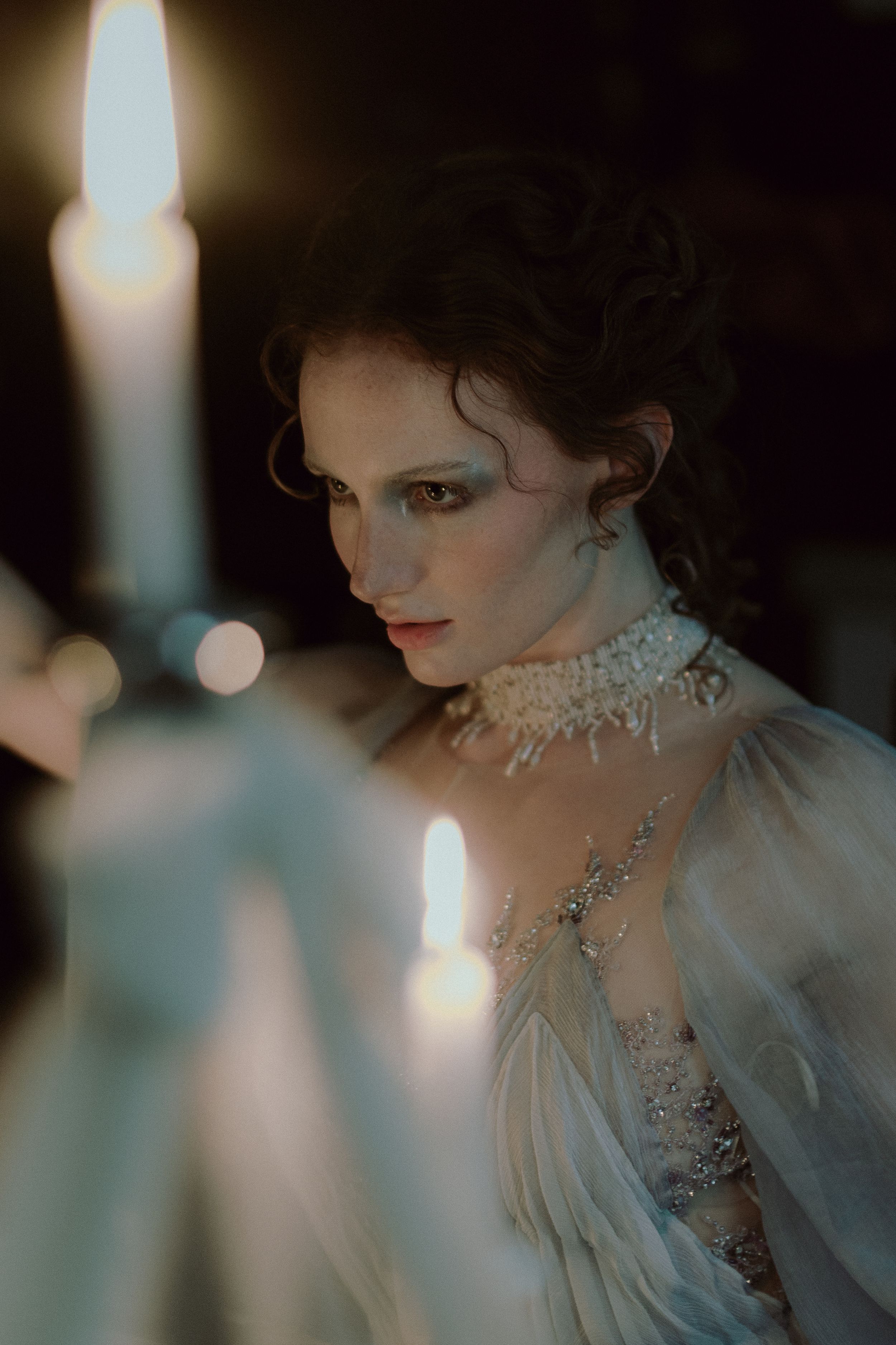 Elegant figure in vintage-inspired bridal attire with crystal necklace and dramatic lighting creating a romantic atmosphere.