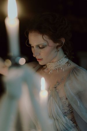 Romantic candlelit portrait featuring delicate lace Victorian collar and sheer fabric in ethereal lighting.
