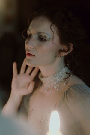Artistic portrait series showing ethereal lighting and delicate crystal details on neck and shoulders against dark background.